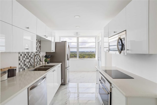 kitchen with white cabinets, decorative backsplash, stainless steel appliances, and sink