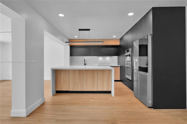 kitchen featuring cooktop, light brown cabinets, oven, and hanging light fixtures