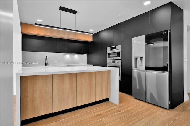 kitchen with kitchen peninsula, stainless steel appliances, hanging light fixtures, and sink