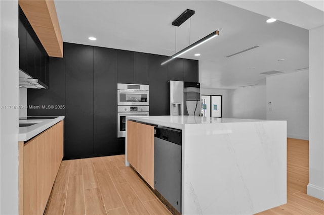 kitchen with decorative light fixtures, stainless steel appliances, and a kitchen island with sink