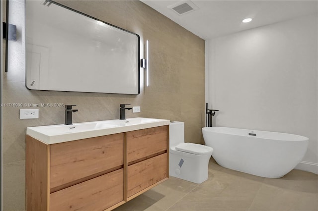 bathroom featuring vanity, backsplash, tile patterned flooring, toilet, and a tub to relax in