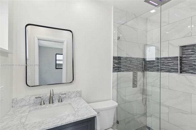 bathroom featuring vanity, toilet, and a tile shower