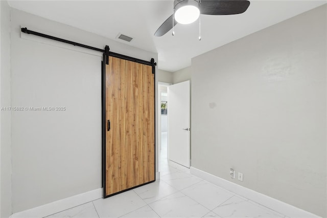 unfurnished bedroom with a barn door and ceiling fan