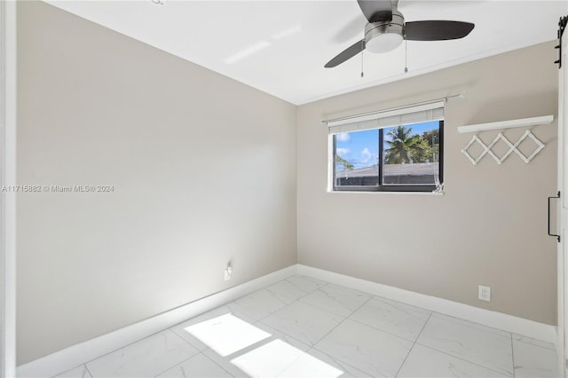 spare room featuring a barn door and ceiling fan