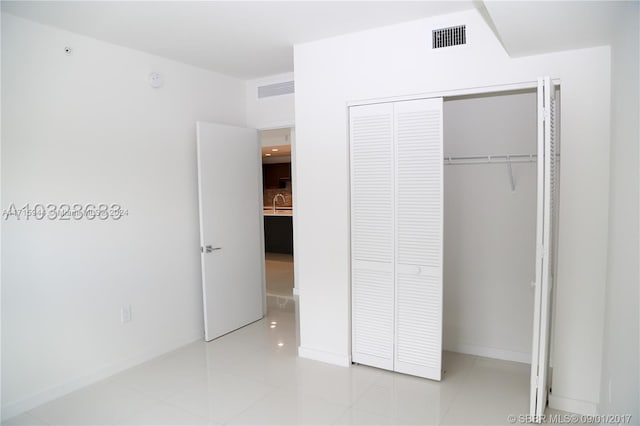 unfurnished bedroom with light tile patterned floors, a closet, and sink