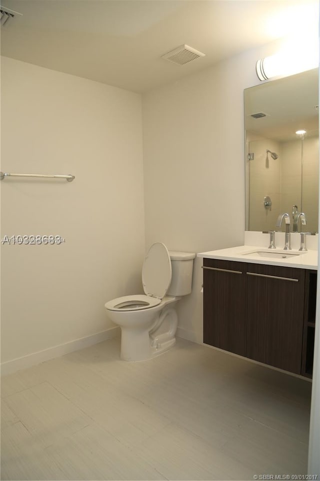 bathroom featuring vanity, toilet, and a shower with door