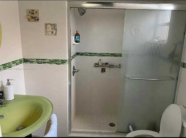 bathroom with toilet, an enclosed shower, and sink