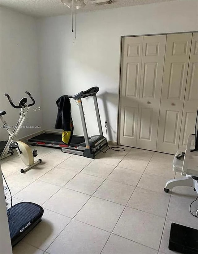 workout room featuring light tile patterned floors and a textured ceiling