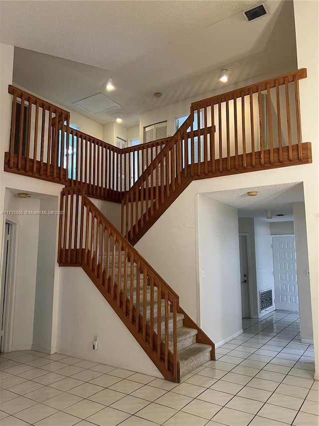 staircase with tile patterned floors and a textured ceiling