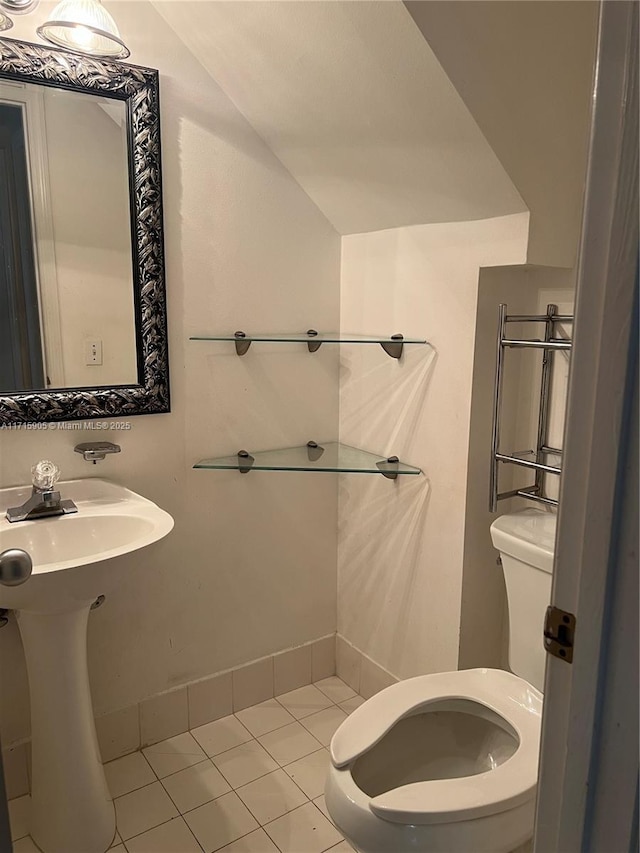 bathroom with tile patterned floors, toilet, lofted ceiling, and sink