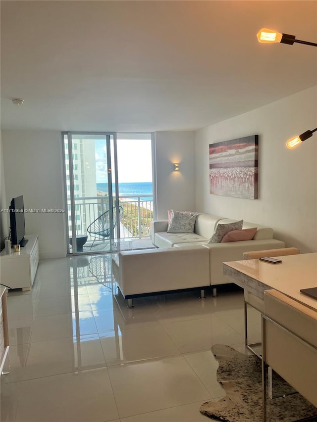 tiled living room featuring a water view and a wall of windows