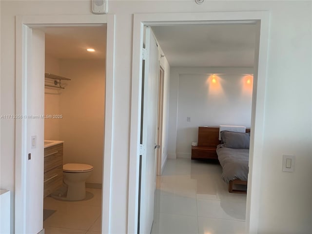 hallway with tile patterned flooring, vanity, and toilet