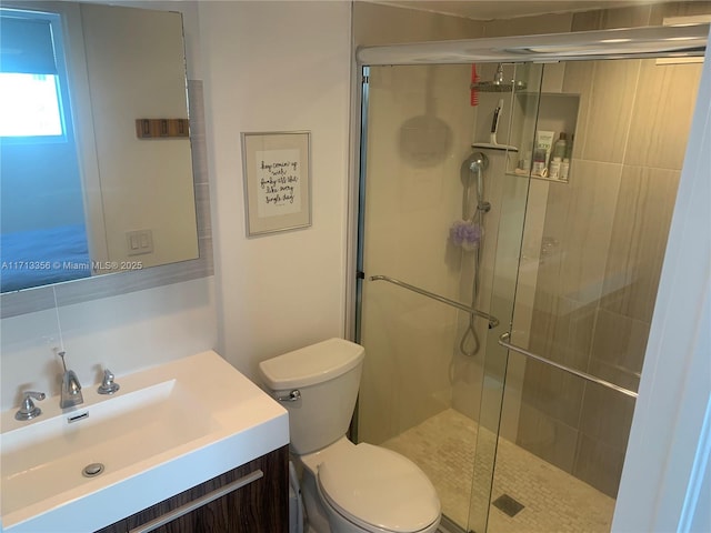 bathroom featuring vanity, a shower with shower door, and toilet