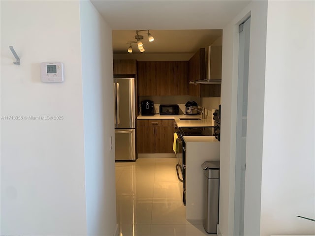 kitchen with sink, electric range, stainless steel fridge, and dark brown cabinets