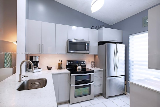 kitchen featuring a sink, white cabinets, light countertops, appliances with stainless steel finishes, and decorative light fixtures