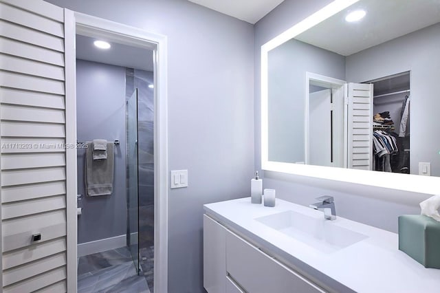 bathroom featuring marble finish floor, a spacious closet, vanity, and recessed lighting