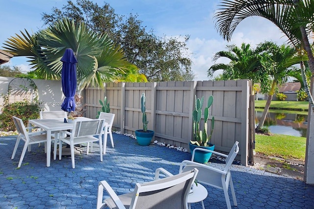 view of patio / terrace with outdoor dining space, a water view, and fence