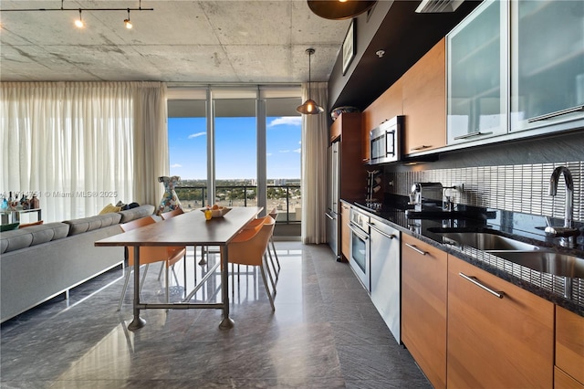 kitchen featuring appliances with stainless steel finishes, backsplash, dark stone counters, sink, and hanging light fixtures