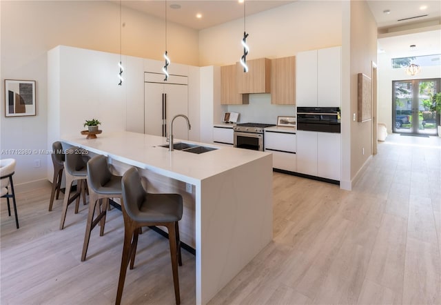 kitchen with modern cabinets, a high ceiling, paneled refrigerator, a kitchen bar, and a sink