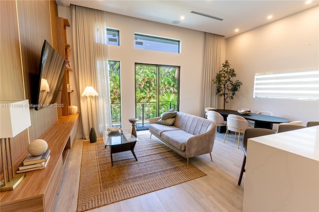 living room with a towering ceiling and light hardwood / wood-style floors