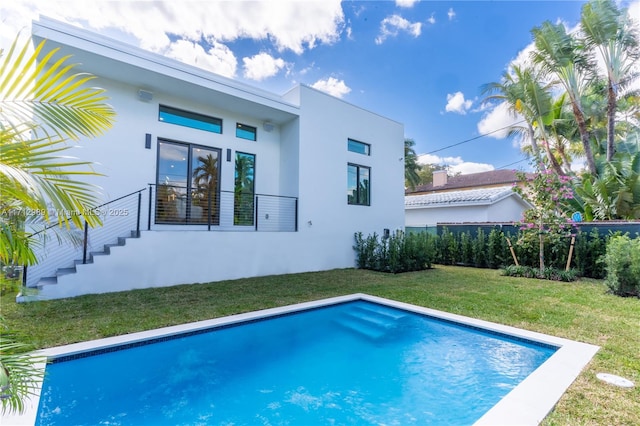 back of property with fence, a yard, french doors, an outdoor pool, and stucco siding