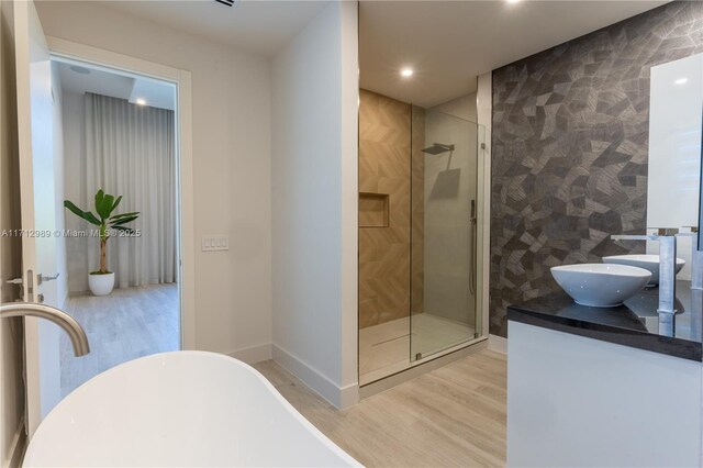 bathroom featuring hardwood / wood-style floors, plus walk in shower, tile walls, and vanity