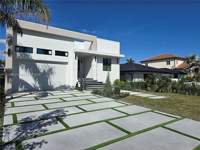 back of house with driveway, an attached garage, and stucco siding