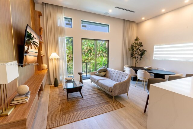 living room featuring a towering ceiling and light wood-type flooring