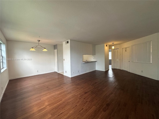 unfurnished living room with a textured ceiling and dark hardwood / wood-style floors