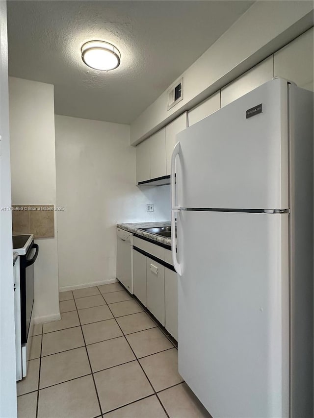 kitchen featuring a textured ceiling, light tile patterned floors, white cabinets, and white appliances