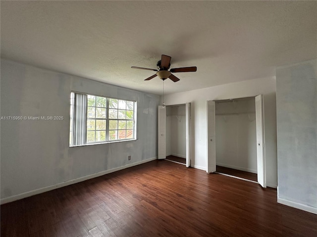 unfurnished bedroom with multiple closets, ceiling fan, and dark hardwood / wood-style floors