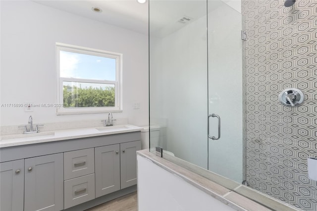 bathroom with hardwood / wood-style floors, vanity, and a shower with shower door