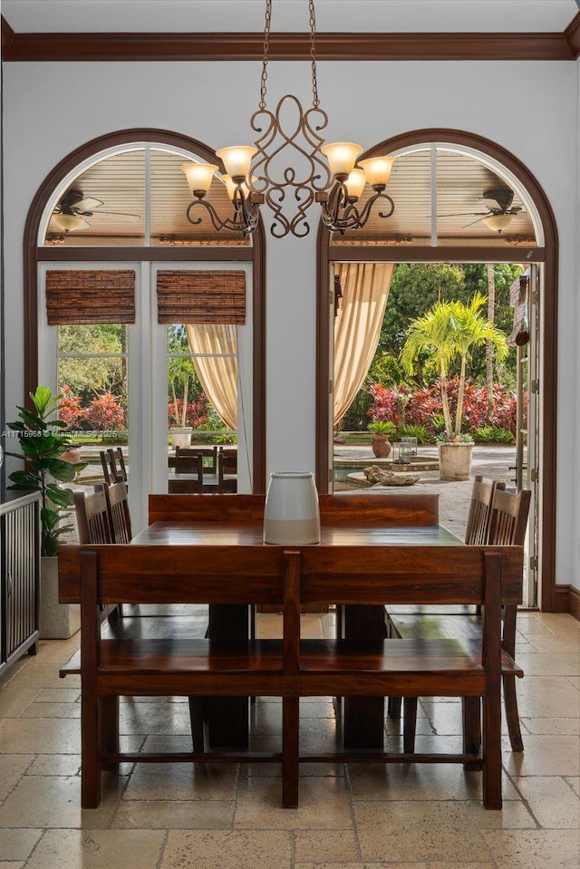 dining space with ornamental molding, stone tile flooring, baseboards, and an inviting chandelier