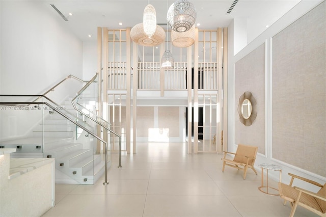 stairs with tile patterned floors and a towering ceiling