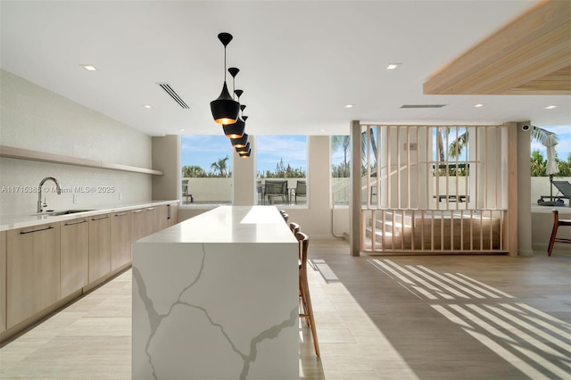 interior space featuring light stone countertops, decorative backsplash, a spacious island, sink, and decorative light fixtures