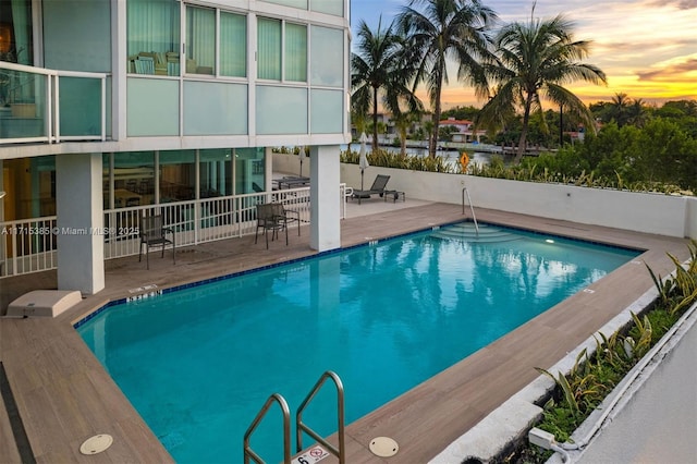 pool at dusk featuring a patio