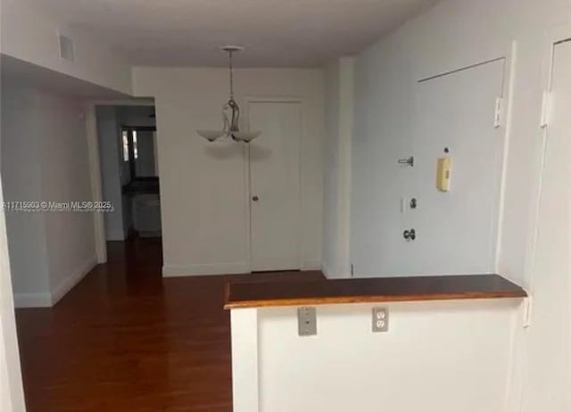 interior space with a kitchen breakfast bar, kitchen peninsula, and dark wood-type flooring