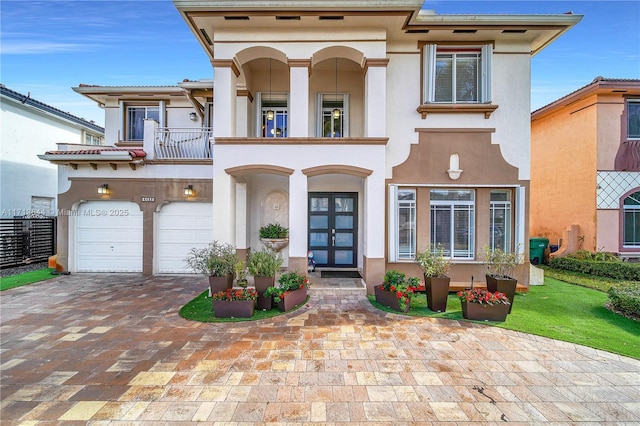 view of front of home featuring a garage, a balcony, and french doors