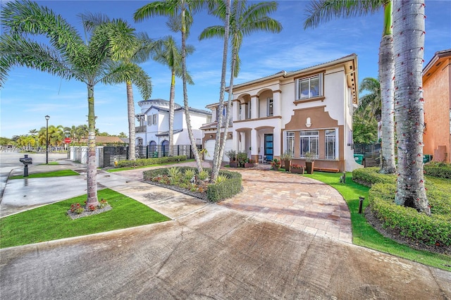 mediterranean / spanish home featuring a balcony, fence, stucco siding, and curved driveway
