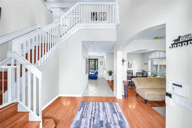 entrance foyer with arched walkways, a healthy amount of sunlight, wood finished floors, and visible vents