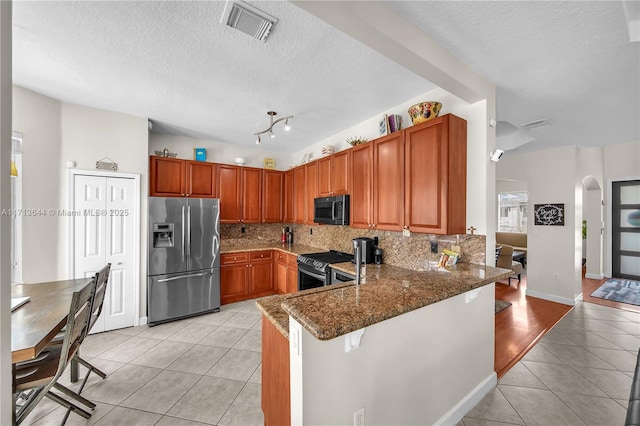 kitchen with kitchen peninsula, a breakfast bar, light tile patterned flooring, and stainless steel appliances