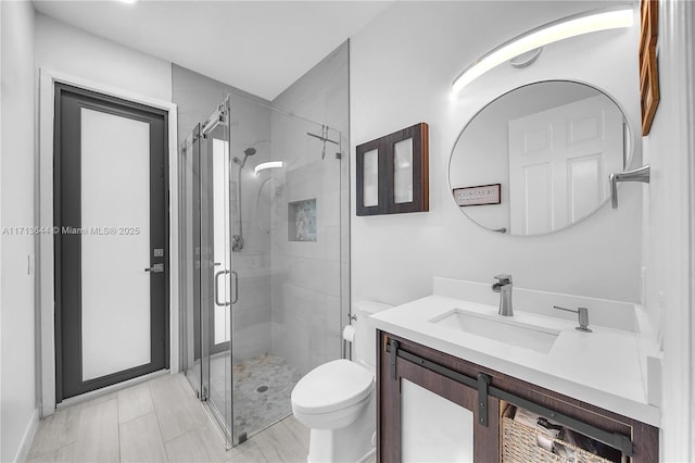 full bathroom featuring a shower stall, toilet, and vanity