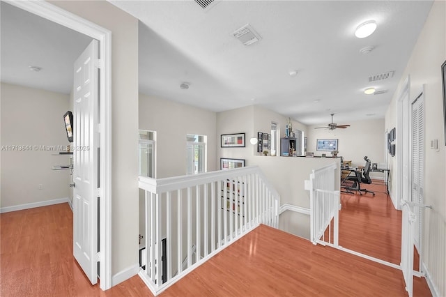 corridor featuring baseboards, wood finished floors, an upstairs landing, and visible vents