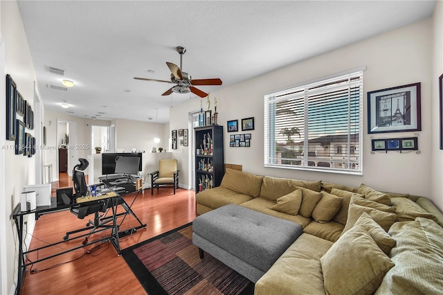 living area with a ceiling fan, wood finished floors, and visible vents