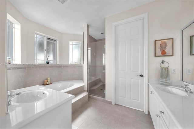 full bath with a garden tub, a sink, a stall shower, tile patterned flooring, and two vanities
