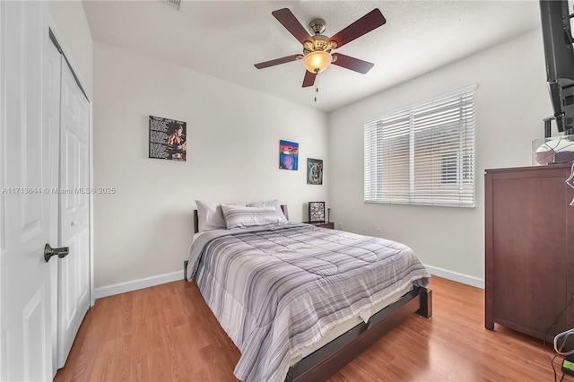 bedroom featuring ceiling fan, light hardwood / wood-style floors, and a closet