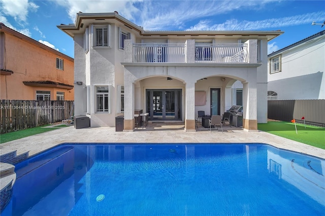back of house featuring stucco siding, french doors, a patio, and a balcony