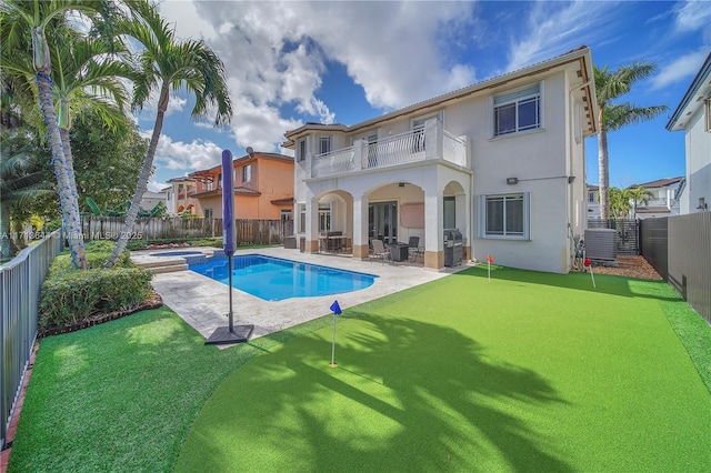 rear view of property featuring a patio area, a balcony, cooling unit, and a pool with hot tub