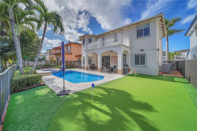 back of house with a fenced backyard, a patio area, a balcony, a pool with connected hot tub, and stucco siding