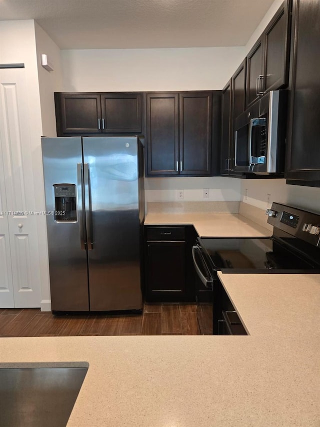 kitchen with dark brown cabinetry, stainless steel appliances, and dark hardwood / wood-style floors